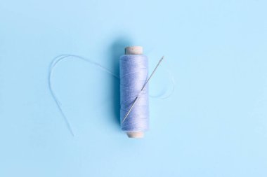 Renk arkaplanında iğne olan iplik makarası