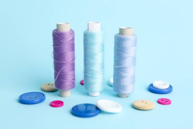 İplik makaraları ve renk arkaplanındaki farklı düğmeler dikiliyor