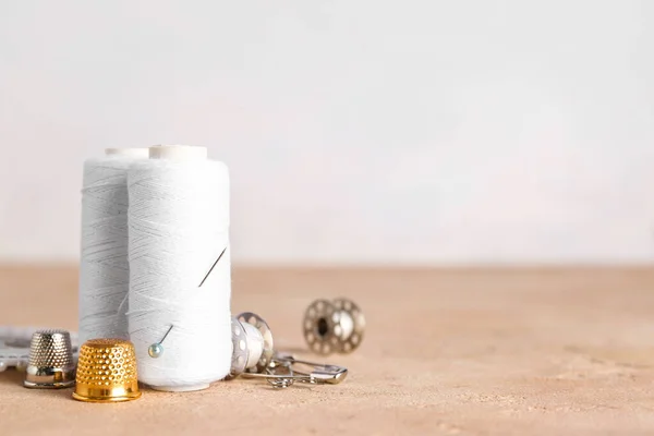 stock image White thread spools and thimbles on color table