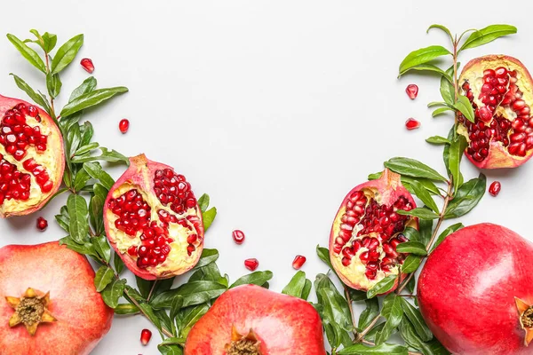 Composition with fresh pomegranates and plant branches on white background, closeup