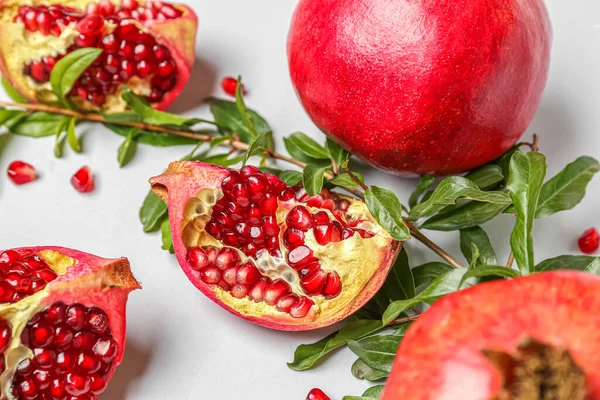 Fresh pomegranates and plant branches on white background, closeup