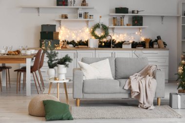 Mutfağın içinde Noel çelengi, yemek masası ve kanepe var.