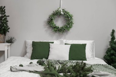 Güzel yatak ve Noel ökseotu çelengi gri duvarda, yatak odasında.