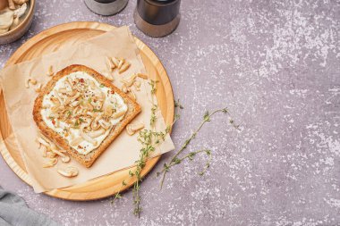 Krem peynirli, mantarlı ve arkaplanda kekik olan ahşap bir tabak lezzetli tost.