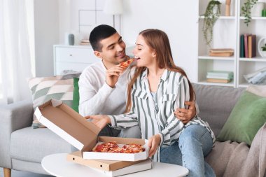 Mutlu genç çift evde lezzetli pizzalar yiyor.