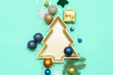 Yeşil arka planda topları, dekoru ve hediyesi olan Noel ağacı şeklinde bir tabak.
