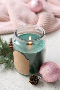Kavanozlu yanan mum, noel balosu, köknar dalları ve beyaz masa üzerindeki koni, yakın çekim.