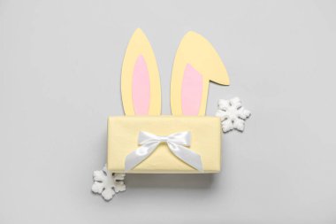 Noel hediyesi ile kağıttan tavşan kulakları ve gri arka planda kar taneleri