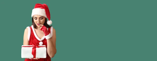 穿着圣诞老人服装的性感年轻女子 背景为绿色 有文字空间 带着圣诞礼物 — 图库照片
