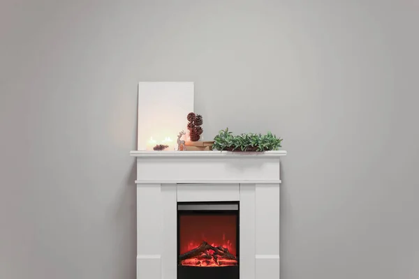 ろうそく クリスマスリース モミのコーンと灰色の壁の近くの暖炉の本と空白のポスター — ストック写真