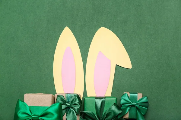 带着绿色背景圣诞礼物的纸兔耳朵 — 图库照片