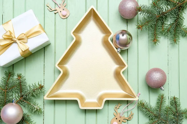 用装饰 礼物和枞树枝条装饰在绿色木制背景上的圣诞树形金属板 — 图库照片