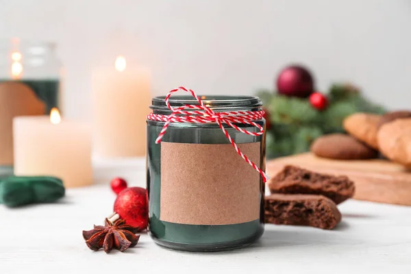 stock image Jar with burning candle, anise and Christmas ball on white wooden table, closeup