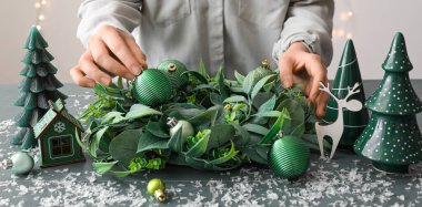 Masada şık bir Noel çelengi yapan kadın, yakın plan.