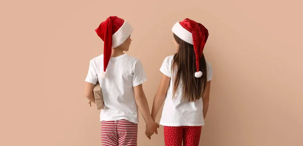 Söta Barn Pyjamas Och Santa Hattar Hålla Händerna Beige Bakgrund — Stockfoto