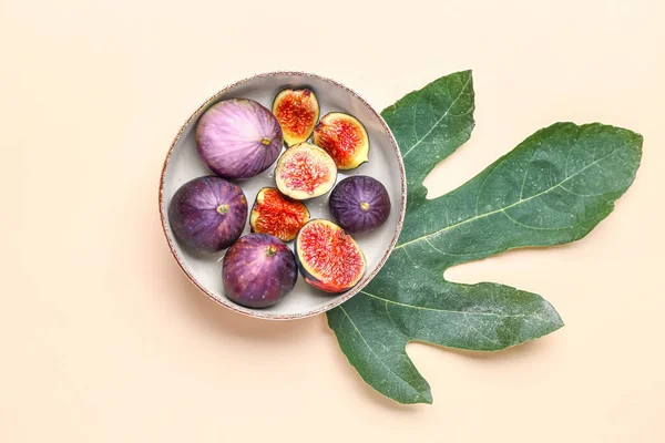 Plate with fresh ripe figs and leaf on color background