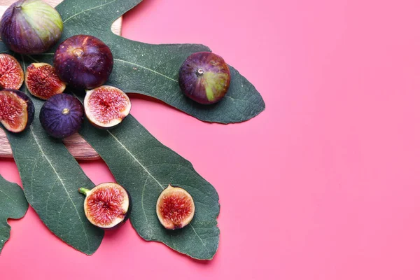 Fresh ripe figs and leaf on color background