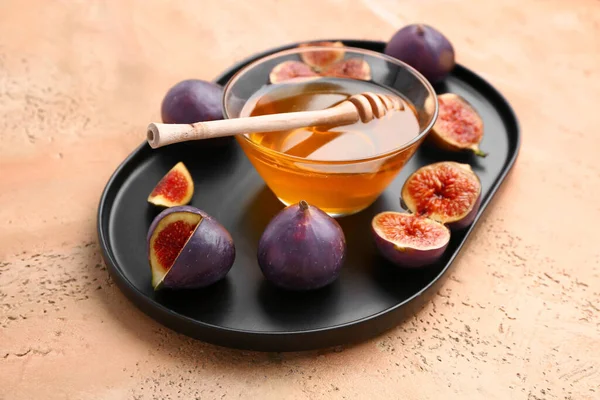 stock image Plate with fresh figs and bowl of honey on color background