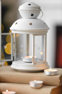 Yılbaşı feneri kitapların üzerinde yanan mumlar, yakın plan.