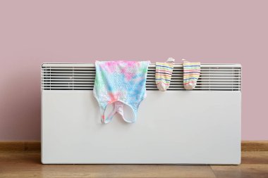 Pembe duvarın yanındaki elektrikli radyatörde sıcak çoraplar ve üst kurutma.