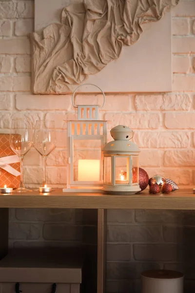 白色砖墙附近的圣诞灯笼 架子上挂着燃烧的蜡烛 眼镜和球 — 图库照片