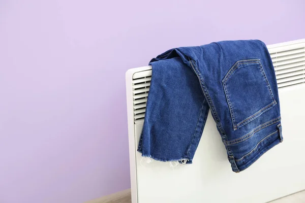 Jeans Drying Electric Radiator Lilac Wall Closeup — Stock Photo, Image