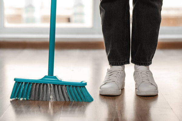 Woman with cleaning broom in room, closeup