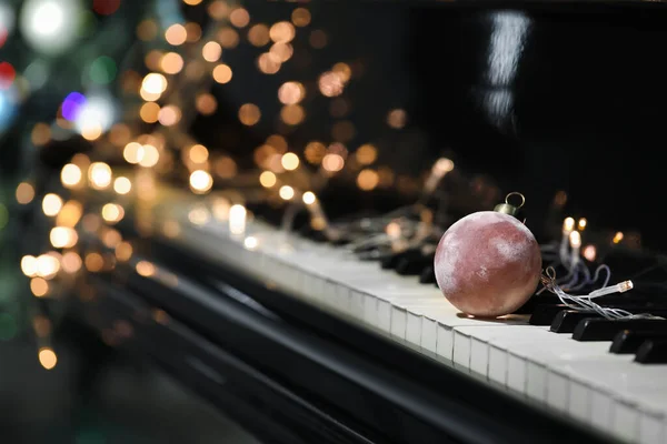 Schöne Weihnachtskugel Und Leuchtende Lichter Auf Schwarzem Piano Nahaufnahme — Stockfoto