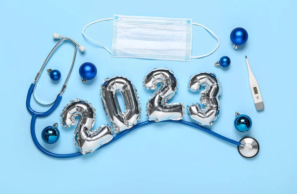 図2023は 青い背景に風船 聴診器 医療用マスク 温度計 クリスマスボールで作られた — ストック写真