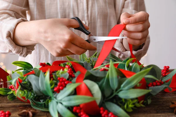 Ahşap Masada Kırmızı Kurdeleyle Noel Çelengi Süsleyen Kadın Yakın Plan — Stok fotoğraf
