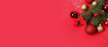 Kırmızı arkaplanda kozalaklı dallar ve Noel süslemeleri ile metin için boşluk ile kompozisyon