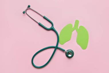 Pembe arka planda steteskoplu yeşil kağıt ciğerler.