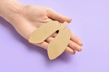 Leylak arka planında kadın eli ve kağıt ciğerler, yakın plan.