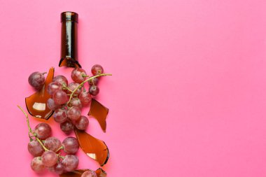 Renkli arka planda üzüm ve kırık şişe kompozisyonu, yakın plan.