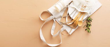 Bej arka planda farklı ekolojik torbalar, sofra takımı ve bitki dalı