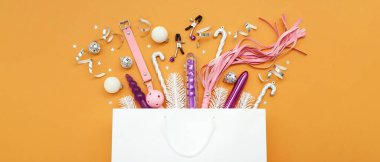 Farklı seks oyuncakları ve turuncu arka planda Noel dekoru olan bir alışveriş çantası.