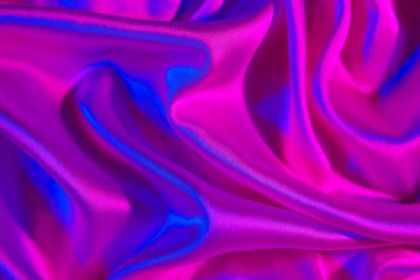 Arkaplan olarak neon ışığı altında buruşmuş ipeksi kumaş