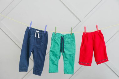 Bebek kıyafetleri gri duvarda asılı.