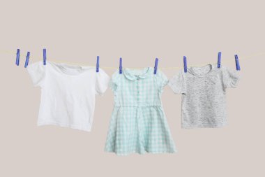 Farklı bebek kıyafetleri renk arkaplanda ipte sallanıyor.