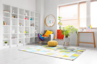 Oturma odasının içinde raf ünitesi, ev bitkileri, koltuk ve gökkuşağı bayrakları