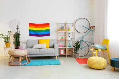 Rahat kanepesi, raf ünitesi, bisikleti ve gökkuşağı bayrakları olan modern oturma odasının içinde.