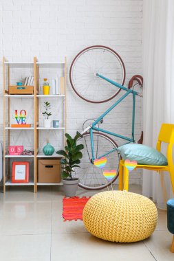 Rafa kaldırma ünitesi, bisiklet ve puf beyaz tuğla duvarın yanında gökkuşağı bayrakları