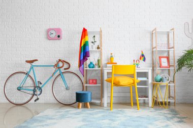 Beyaz tuğla duvarın yanında bisiklet ve gökkuşağı bayraklı işyeri