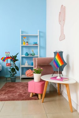 Güzel bitkiler, raf ünitesi ve masa üzerinde gökkuşağı bayrağı olan modern lamba.