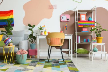 Renkli duvarın yanında ev bitkileri ve gökkuşağı bayrakları olan şık bir iş yeri.