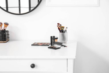 Makyaj sanatçısının işyeri dekoratif kozmetik ürünleriyle aydınlık duvarın yanında