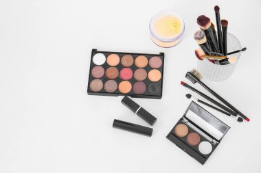 Makyaj sanatçılarının beyaz masasında fırça ve dekoratif kozmetik ürünleri olan tutucu.