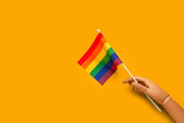 Sarı zemin üzerinde LGBT bayrağı olan tahta el.