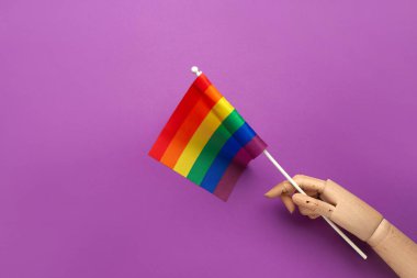 Mor zemin üzerinde LGBT bayrağı olan tahta el.