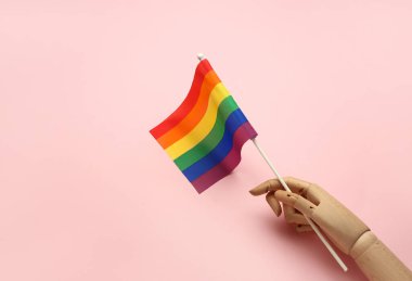 Pembe arka planda LGBT bayrağı olan tahta el.